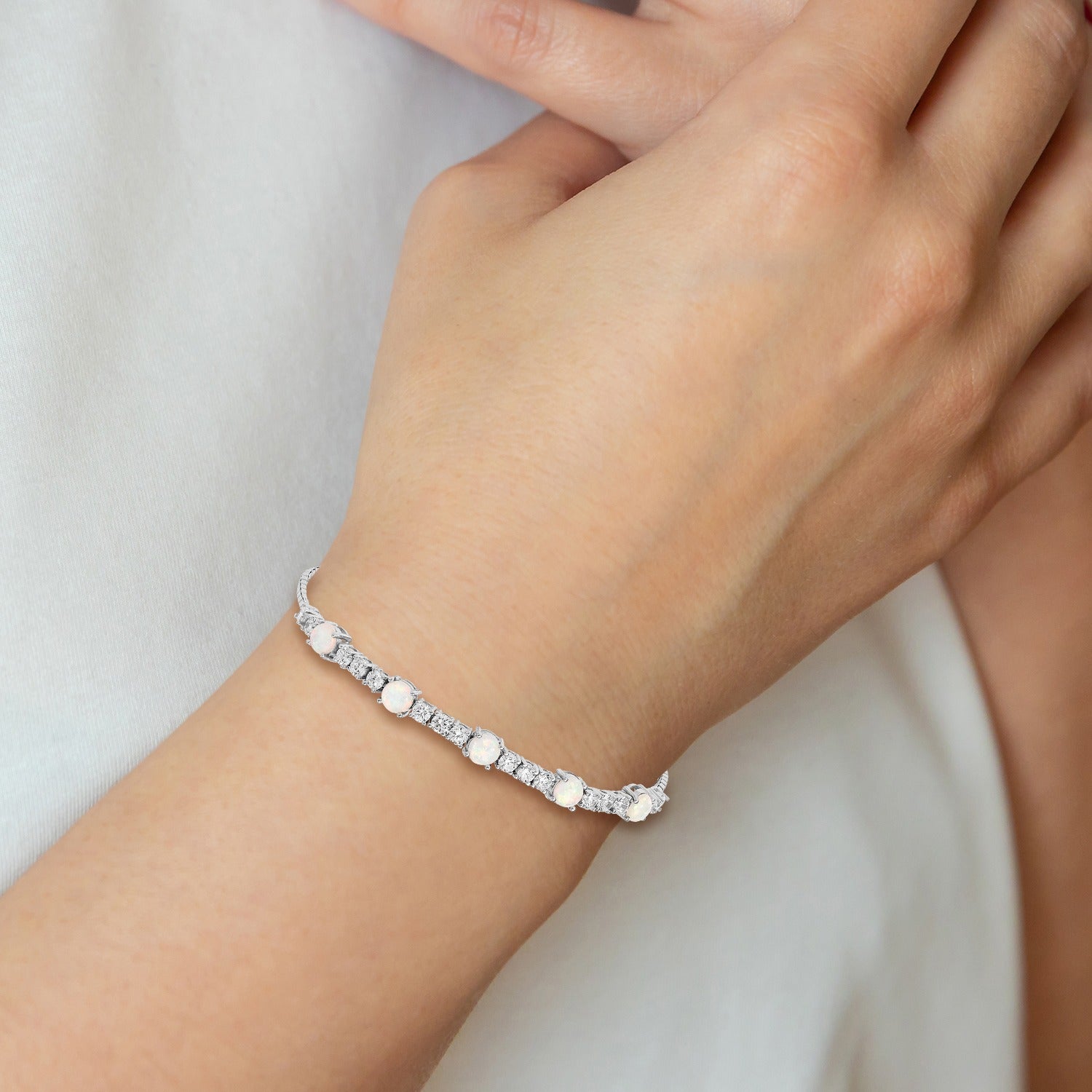 Hand wearing a delicate gemstone and diamond silver bracelet from Fine Color Jewels