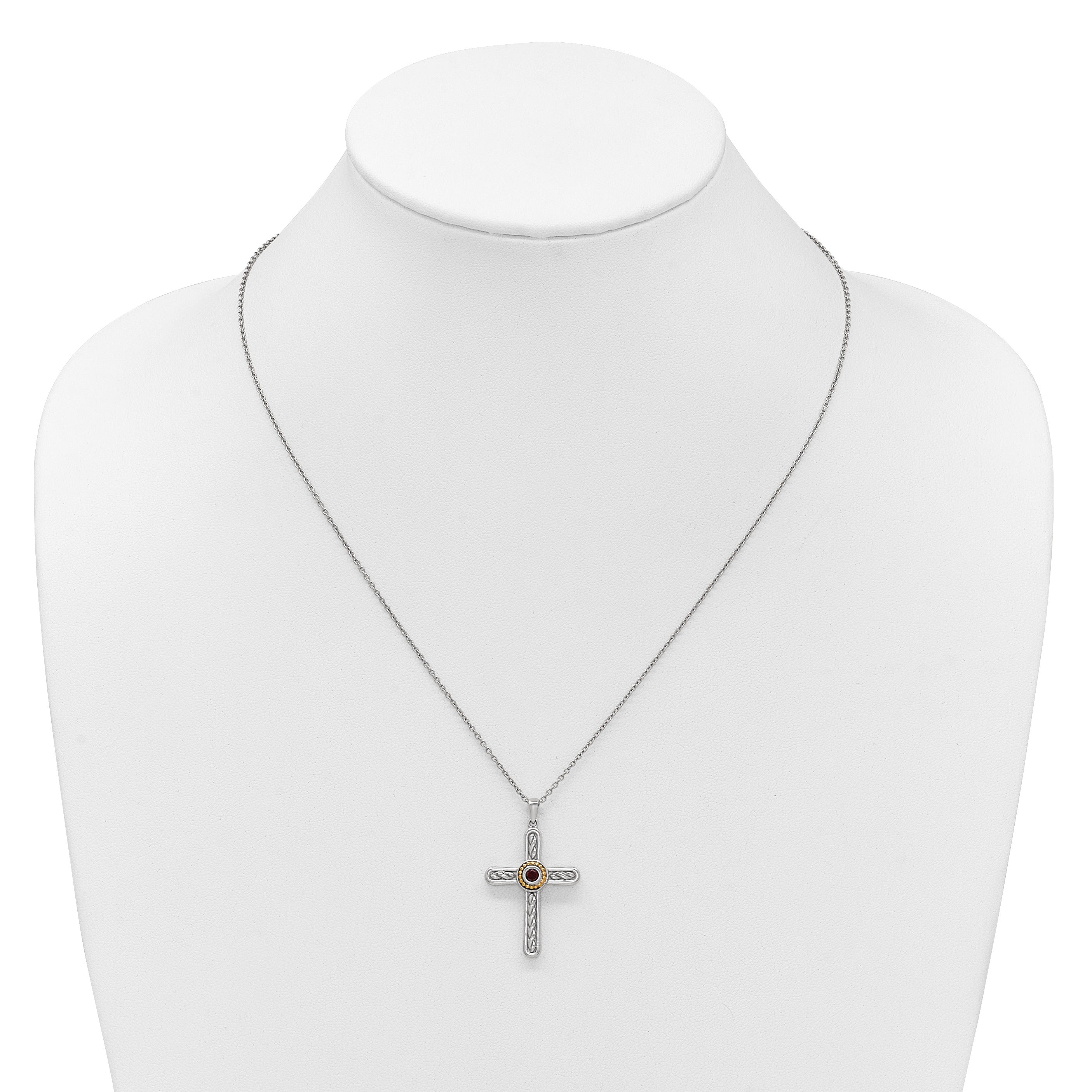 Silver cross pendant necklace with intricate design and central red gemstone on white display