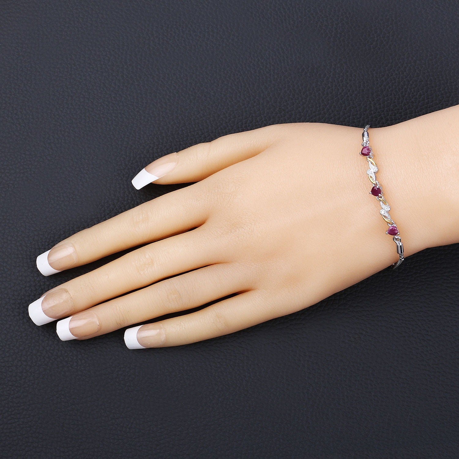 Hand wearing a delicate gemstone bracelet with red stones on black background, Fine Color Jewels