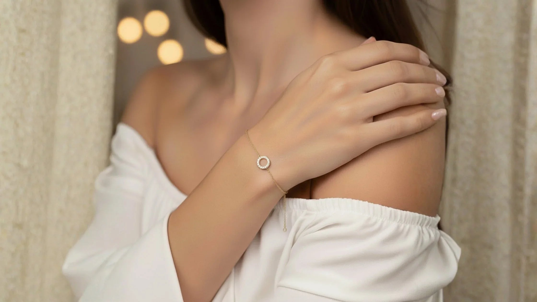 Close-up of a woman's wrist wearing a delicate 10k gold bracelet with an adjustable chain. The bracelet features a small, sparkling pave diamond "O" initial charm, reflecting a personalized and elegant jewelry style.