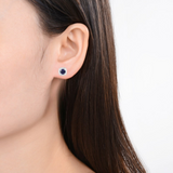 Model showcasing Natural Sapphire Halo Earrings With Moissanite Accents White Gold and Light Blue Halo Stud Earrings