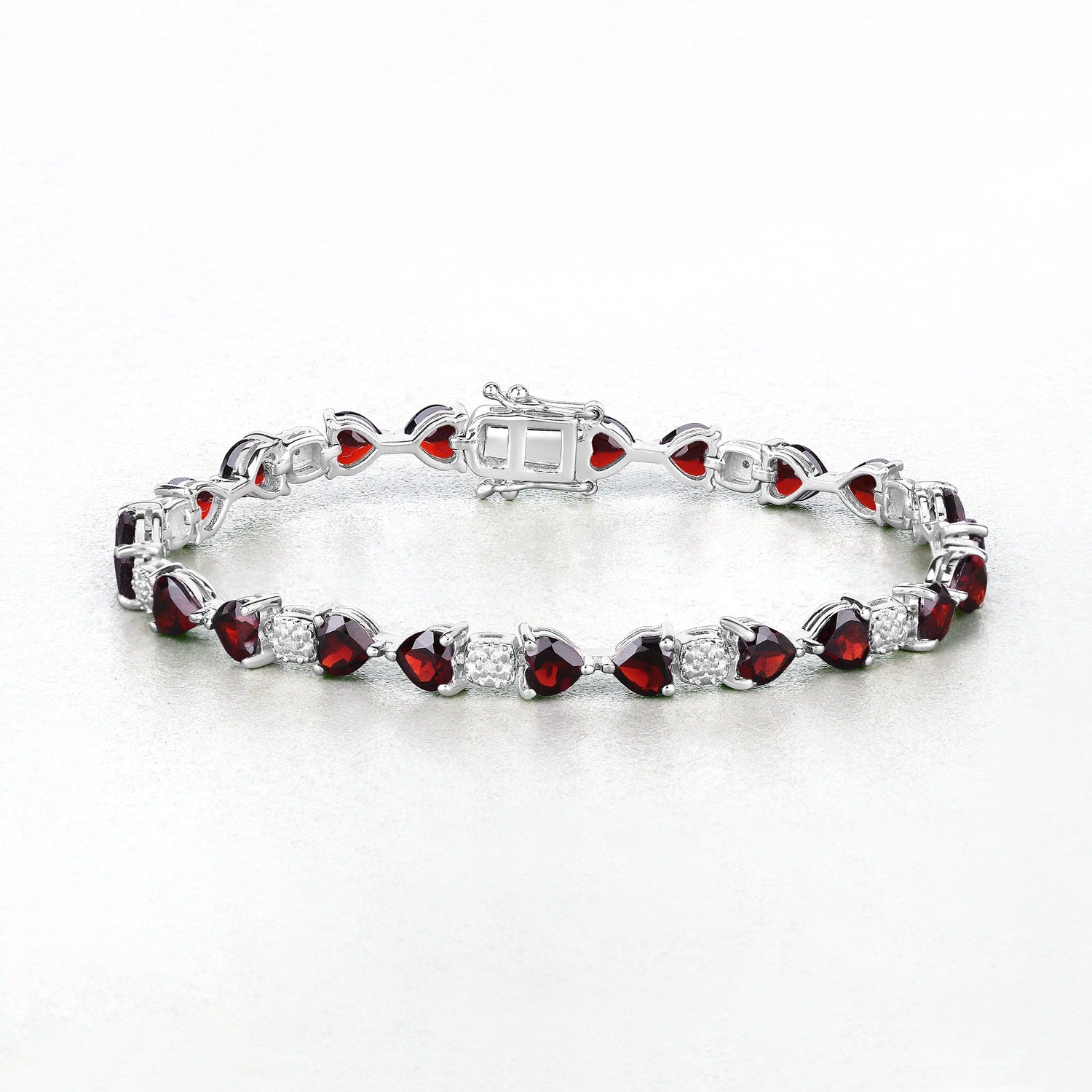 Silver tennis bracelet with heart-shaped red gemstones and clear accents on white background